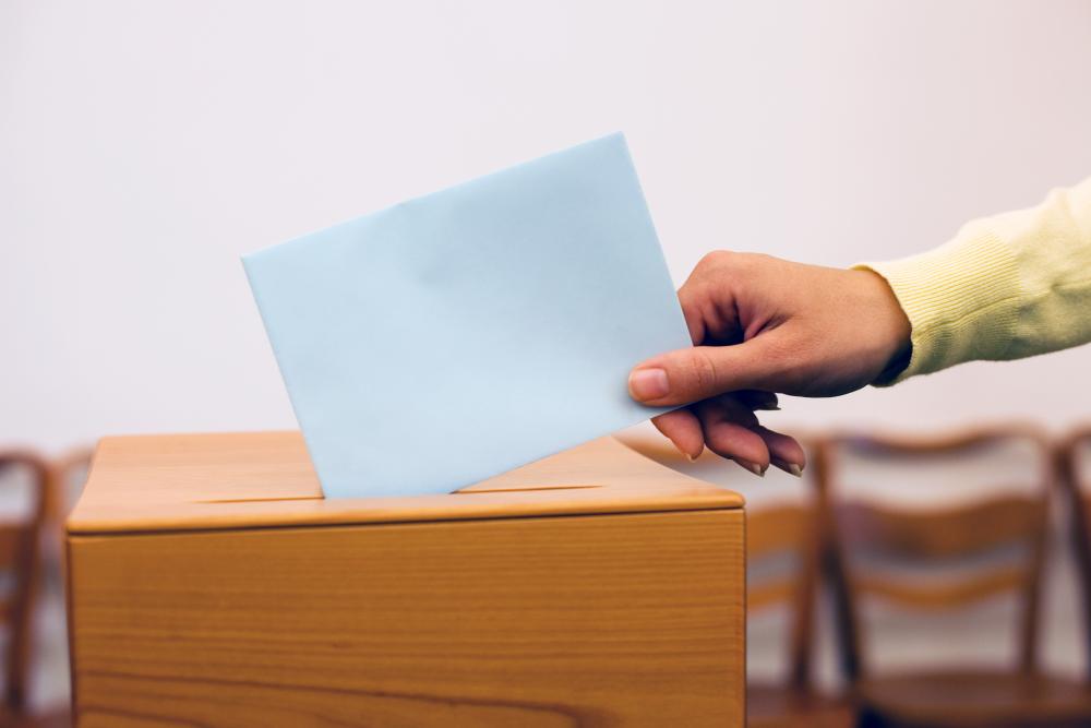 A vote is put in a ballot box. Photo.
