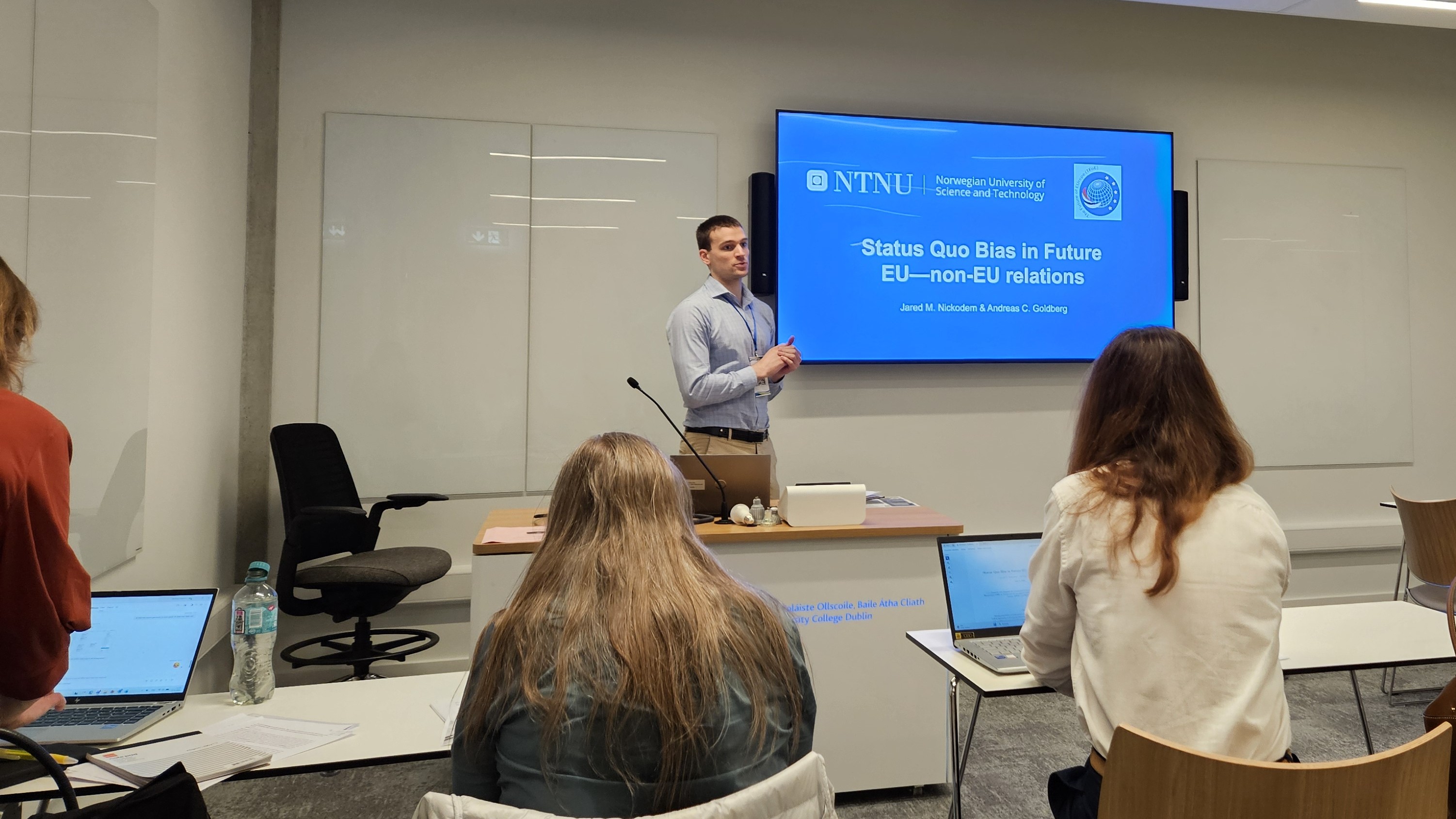 Photo. Man in front of classroom with a presentation titled "Status Quo Bias in Future EU - non-EU relations"