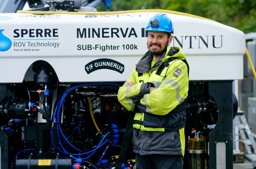 An employee standing in front of an underwater drone used for offshore operations