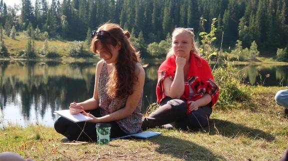 Two women sitting by a lake