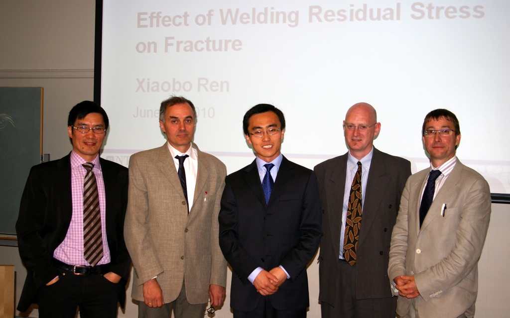 Professors and students standing in front of a projector screen. Photo