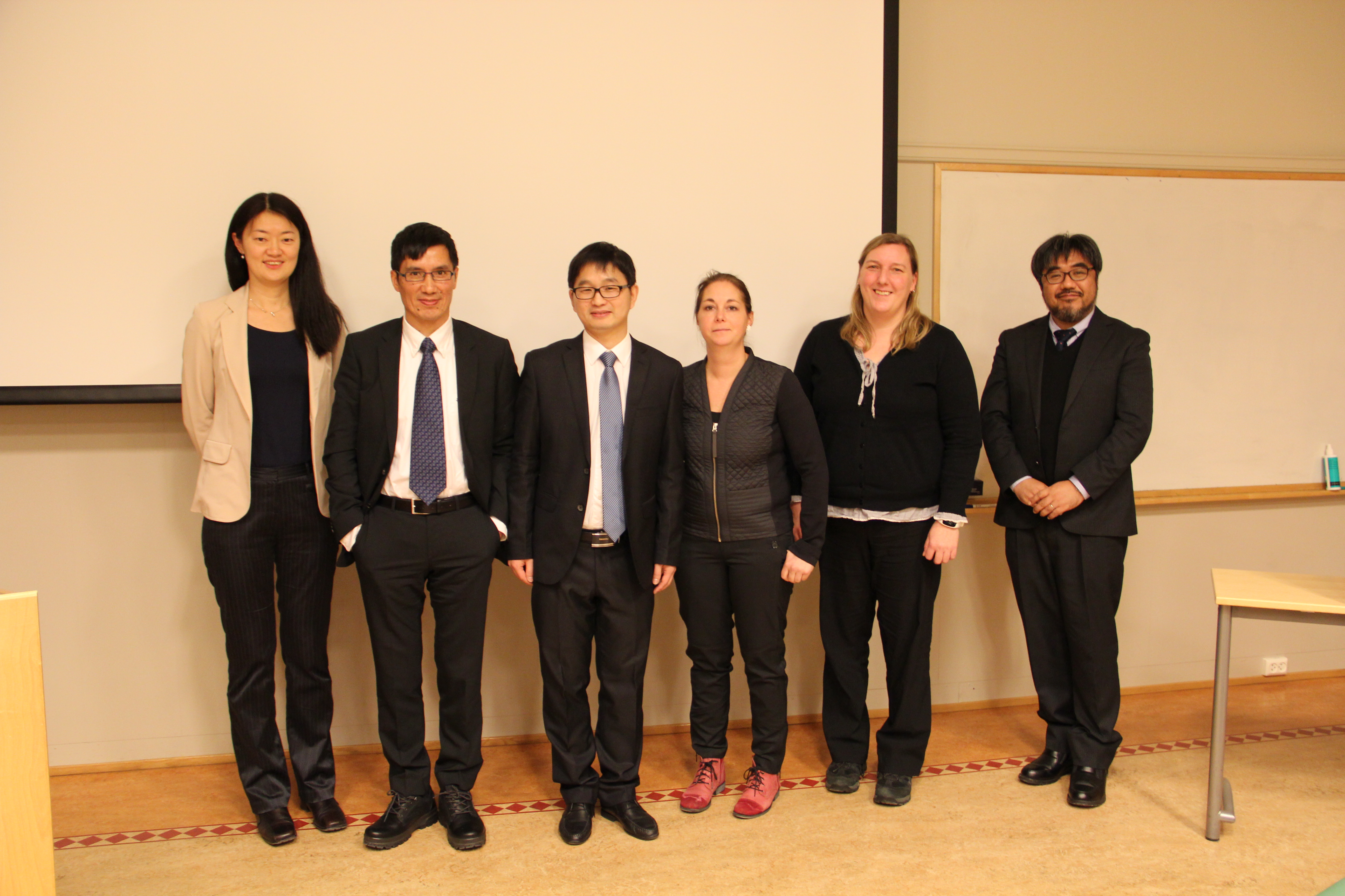 Professors and students standing in front of a projectorscreen. Photo