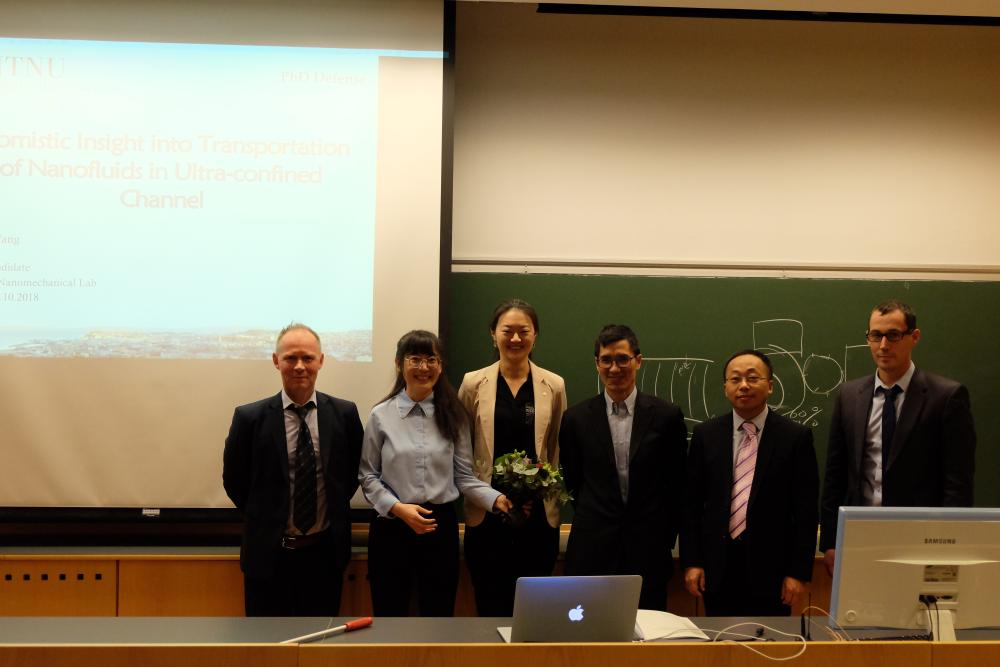 Professors and students standing in front of a projector and blackboard. Photo.