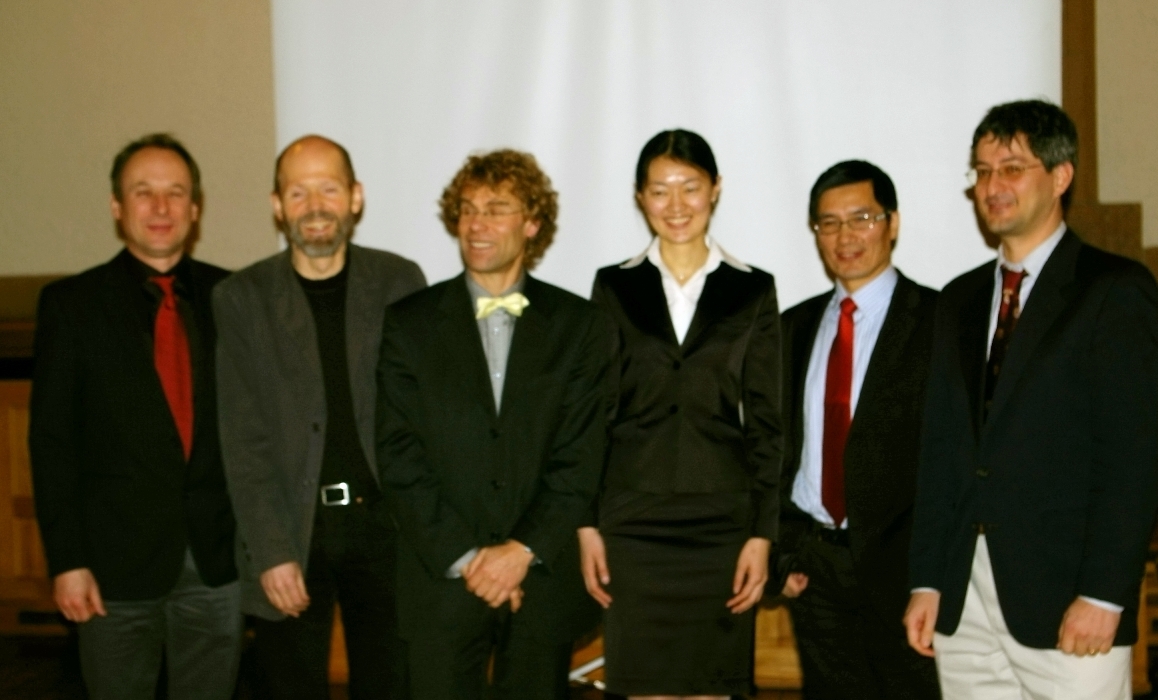 Professors and students standing in front of a projector screen. Photo.