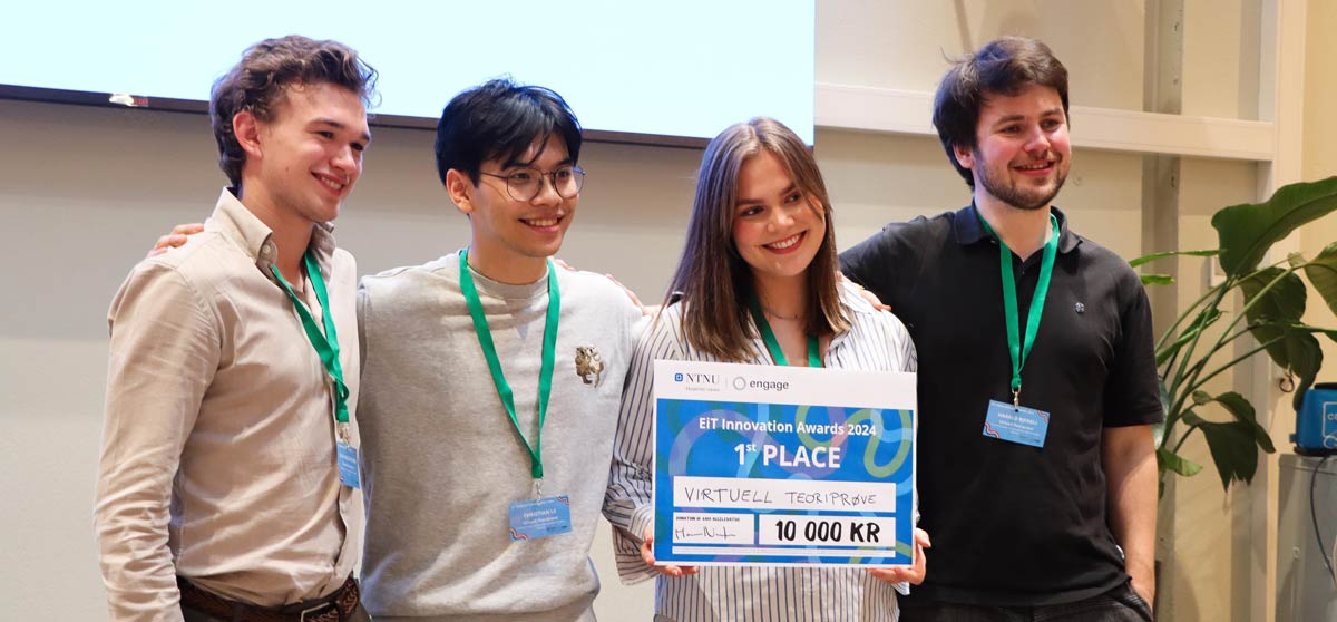 Students on stage holding prize and smiling