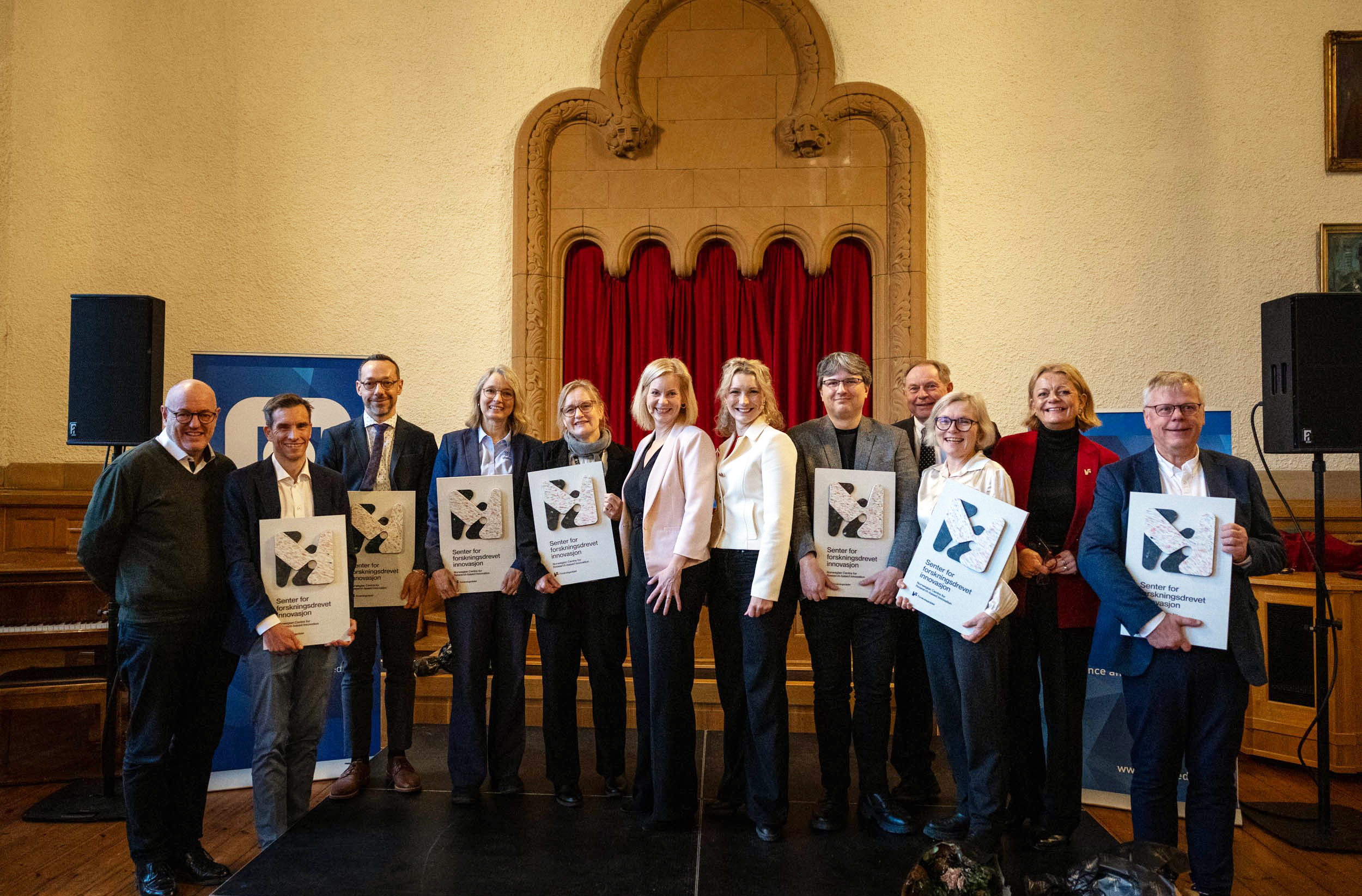 A group of people, most of them displaying SFI plaques from the Research Council of Norway.