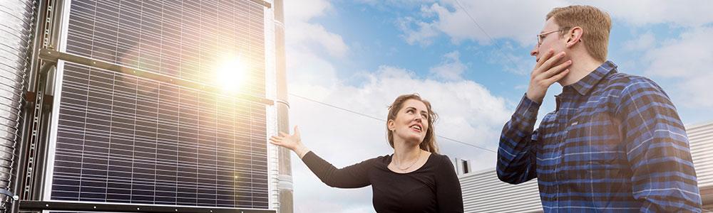 Two people standing in front of solar panels