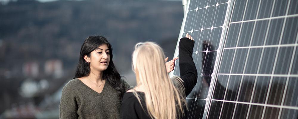 Two students standing beside solar panels. Photo: Geir Mogen/NTNU