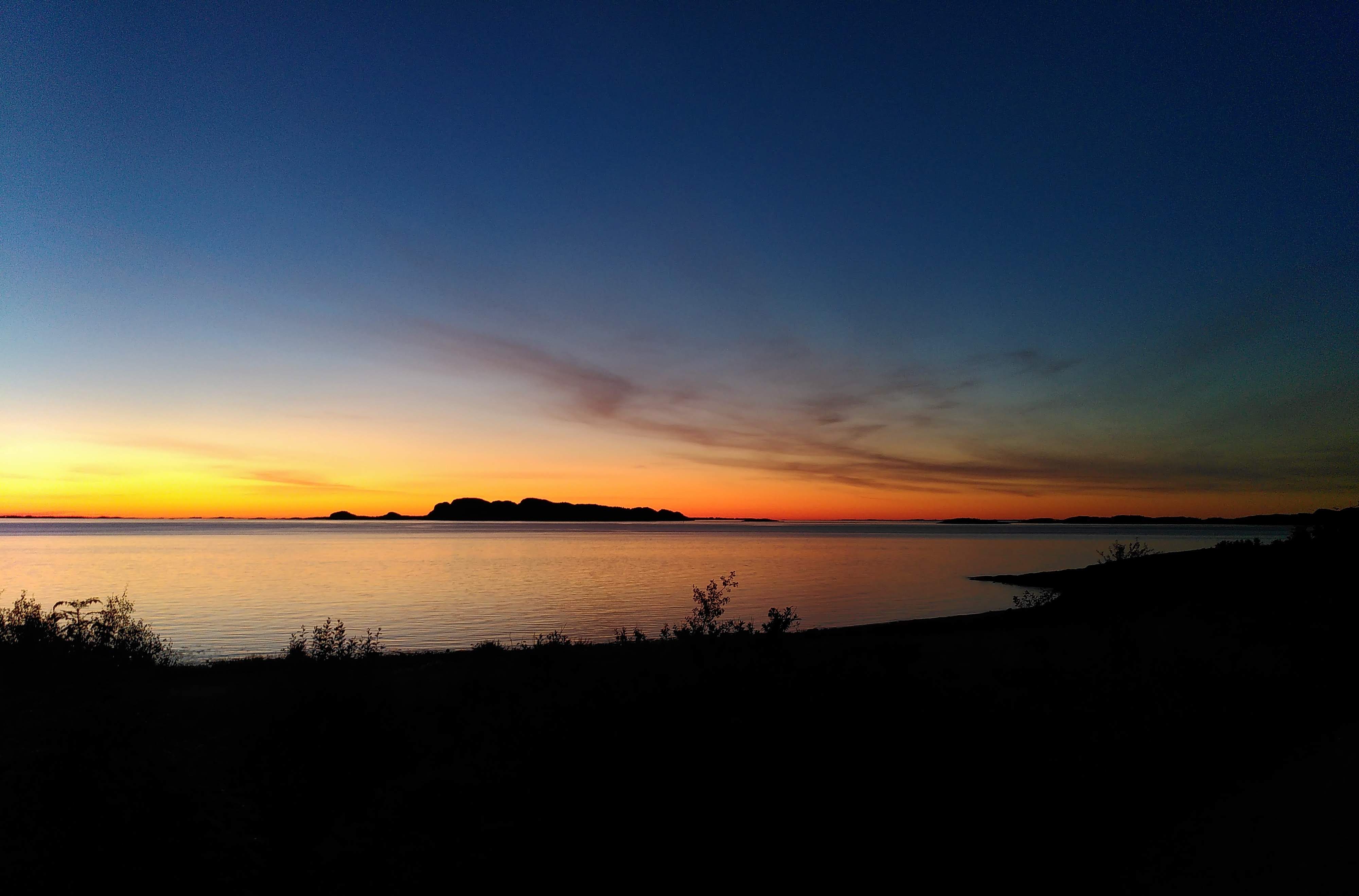 Photo of sunset by a lake or fjord.